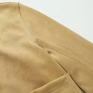 Detail of camel suede jacket featuring white contrast stitching on shoulder and pocket