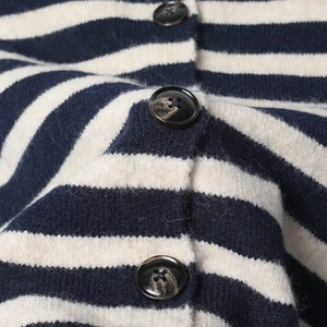 Macro shot of striped knit cardigan fabric with marble texture round buttons detail