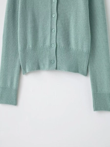 Detailed macro view of mint green knit cardigan with ribbed cuffs and matching buttons