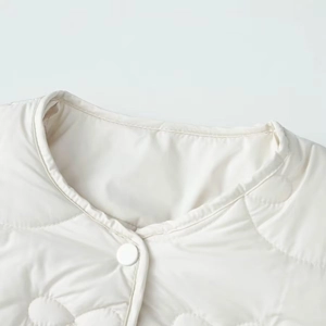 Detail of quilted floral pattern and snap button on cream round neck vest