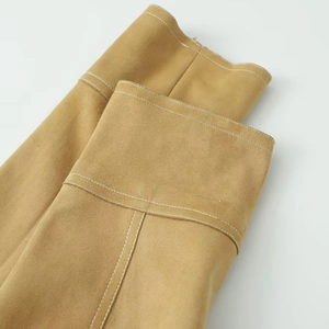Close-up of camel suede jacket detail featuring white contrast stitching and soft texture