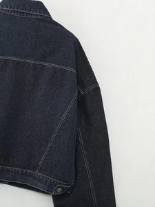 Détail du dos d'une veste en jean indigo avec surpiqûres et bouton métallique à la taille