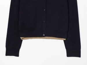 Detail of color-block knit polo cardigan featuring dark blue fabric and beige hem accents