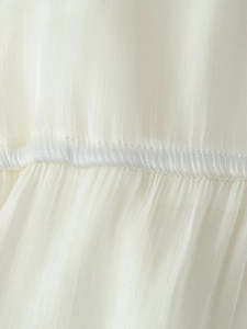 Detail of white ruffle long dress showing semi-sheer fabric texture and fine pleated seams