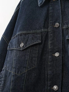 Détail de veste en jean bleu foncé avec boutons argentés et coutures précises