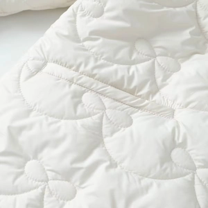 Close-up of white quilted fabric with refined floral pattern and detailed stitching
