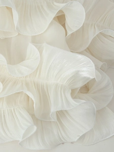 Macro shot of white pleated fabric with ruffle edges and delicate chiffon texture detail