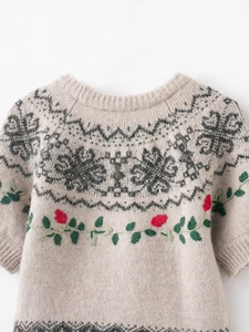 Detailed close-up of vintage beige knit sweater with floral embroidery and jacquard pattern