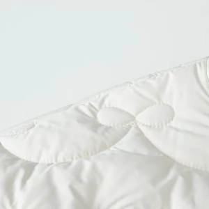 Close-up of white quilted jacket fabric with decorative bow embroidery details