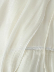 Close-up of cream ruffled fabric with vertical pleats and fine stitching details
