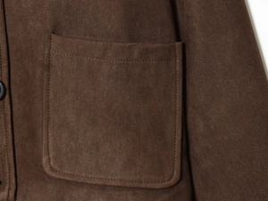 Detail einer dunkelbraunen Wildlederjacke mit Präzisionsnähten auf einer quadratischen Tasche