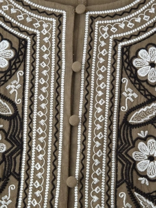 Close-up of olive green embroidered shirt with ethnic patterns and fabric-covered buttons