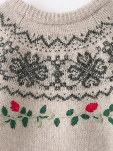Detail of vintage knit sweater showing ribbed crew neck with floral embroidery and jacquard