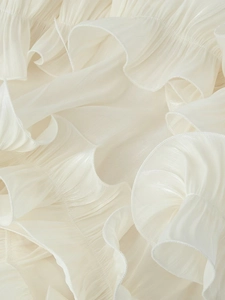 Macro shot of delicate tiered ruffles on creamy white chiffon maxi dress fabric