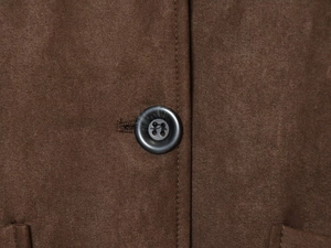Makroaufnahme der braunen Velourslederjacke mit Marmorknopf und feinen Nähten im Detail