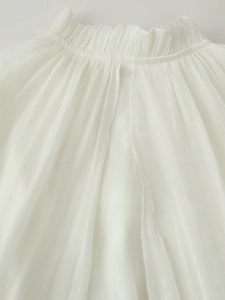 Close-up of white pleated long dress featuring elastic ruffled waist and chiffon texture