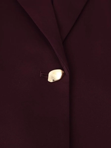 Detailed close-up of a gold organic metal button on a burgundy slim-fit blazer