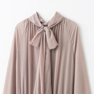 Elegant dusty pink bow-tie dress in flowing fabric with long raglan sleeves and fluid drape