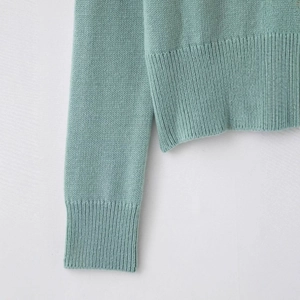 Light mint green knit cardigan with ribbed cuffs and hem on minimalist background