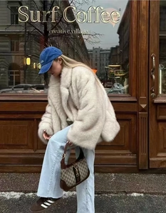 Detail of elegant white faux fur coat paired with denim jeans in a street style shot