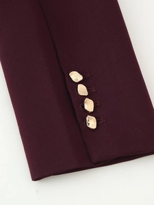 Detailed macro view of burgundy blazer cuff with four unique irregular gold metal buttons