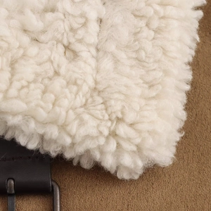 Detailed close-up of soft white fleece fabric with black leather strap and metal buckle