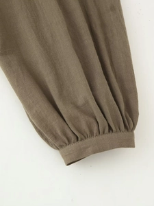Detail of army green embroidered linen shirt showing puffy sleeves and textured fabric