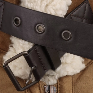 Detail of brown suede jacket showing fuzzy shearling lining and a buckle belt with metal eyelets