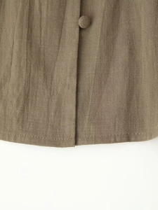 Close-up detail of fabric texture and matching cloth button on a khaki linen shirt