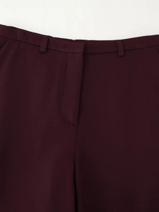 Close-up of dark burgundy tailored trousers featuring waist belt loops and hidden placket