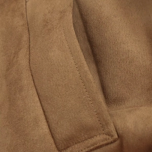 Detail of double stitching on brown suede jacket pocket showing matte texture