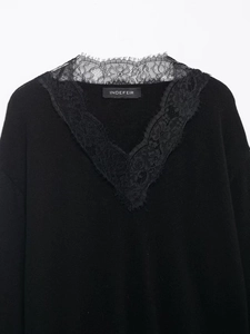 Detailed close-up of V-neckline with delicate floral lace trim on black knitted sweater