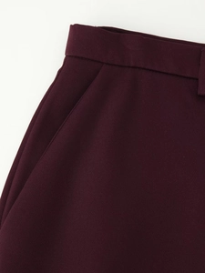 Detailed view of deep burgundy trousers showing waistband loops and side slant pockets