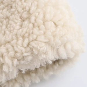 Macro shot of off-white sherpa fleece texture with soft curly fibers for winter jackets