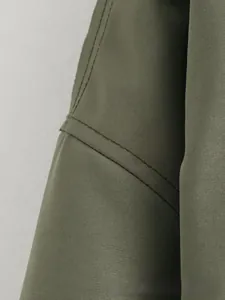 Détail d'épaule de veste bomber vert olive avec tissu sergé robuste et double couture