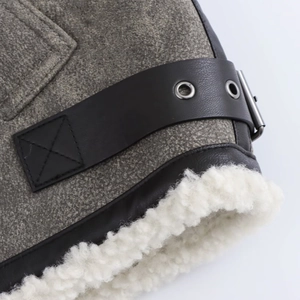 Detalle de cuello de chaqueta de lana con correas de cuero negro y forro de borreguillo
