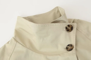 Detail of high stand collar and tortoiseshell buttons on beige twill trench coat