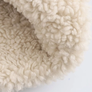 Close-up of soft beige sherpa fleece texture on a warm double-sided zipper jacket