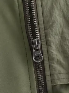 Gros plan détaillé de la fermeture éclair métallique sur une veste bomber vert olive