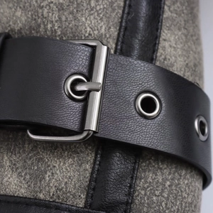 Detalle de correa de cuero negro con hebilla metálica sobre chaqueta de tweed gris