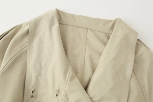 Detail of khaki trench coat lapel with double-breasted buttonholes and textured twill fabric