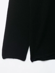 Detail of black knit sweater showing the soft texture and side slit craftsmanship