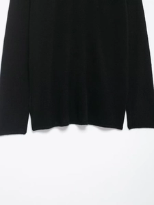 Detailed macro view of the knitted fabric texture on the black V-neck sweater hem and cuffs