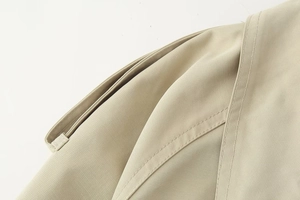 Macro detail of the epaulet and double-stitched twill fabric on the beige trench coat