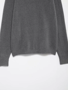 Close-up of dark grey knit sweater showing ribbed cuffs and fine texture detail