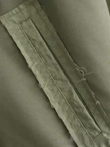 Détail des bordures effilochées et des coutures de qualité sur le bomber vert olive