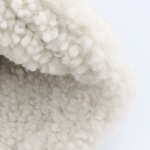 Primer plano de piel sintética blanco crema con textura densa de borreguito rizado