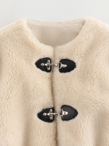 Detail of beige faux fur jacket showing unique silver metal buckles and black heart-shaped base