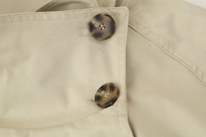 Macro detail of khaki double-breasted trench coat with tortoiseshell buttons and twill fabric