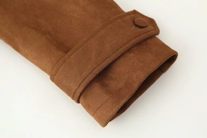 Detail of sleeve cuff with adjustable strap and fabric button on brown suede jacket
